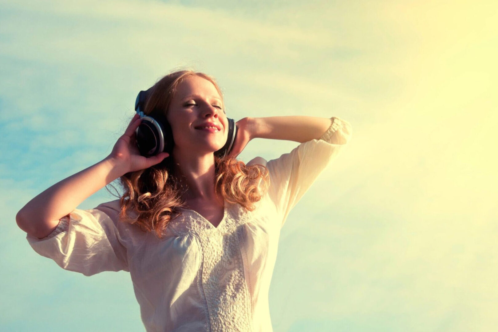 A woman with headphones on is listening to music.