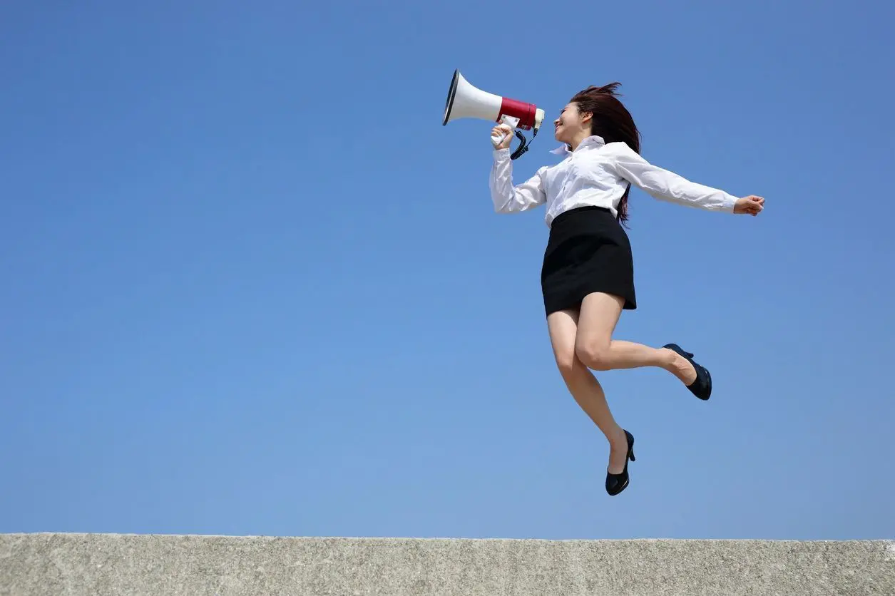 A woman is jumping in the air with a megaphone.