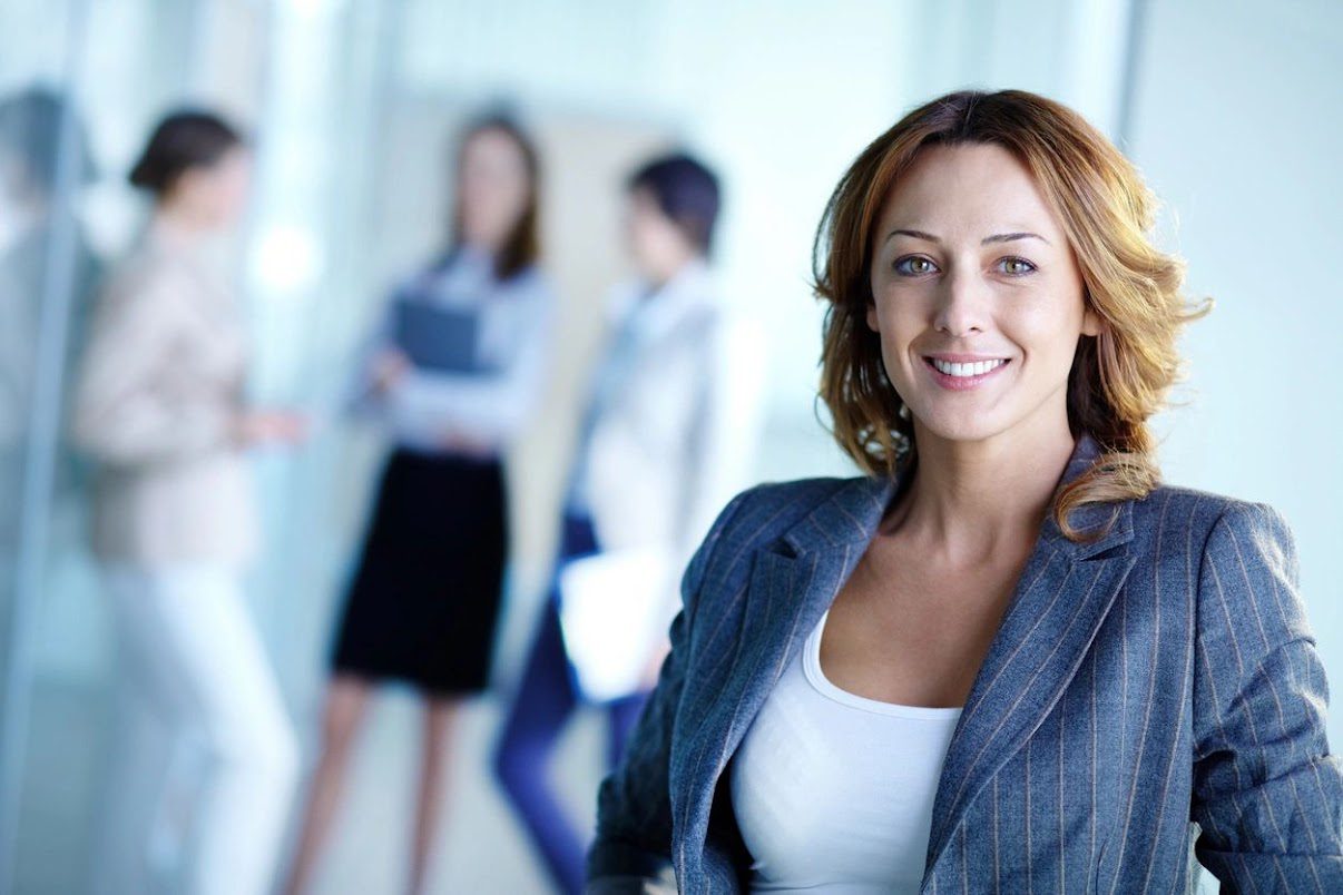 A woman in business attire standing next to other women.