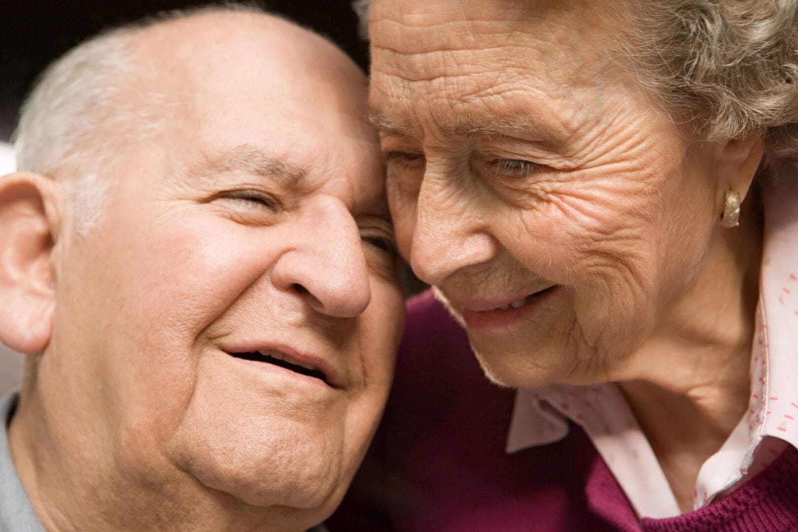An Elderly Couple Smiling At Each Other